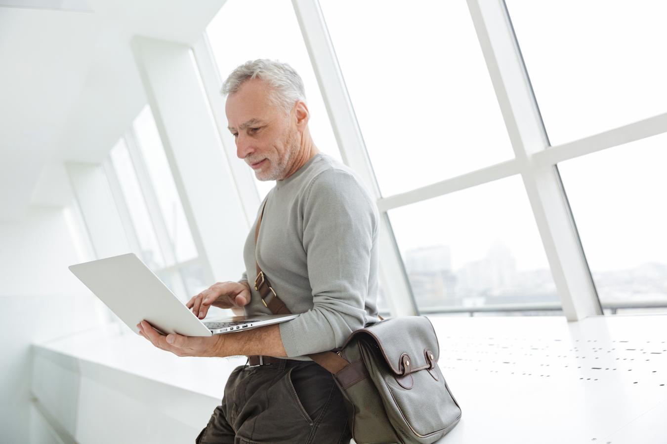 an older man working on his laptop with a shoulder bag corporate swag corporate swag top company swag ideas great swag corporate swag swag box