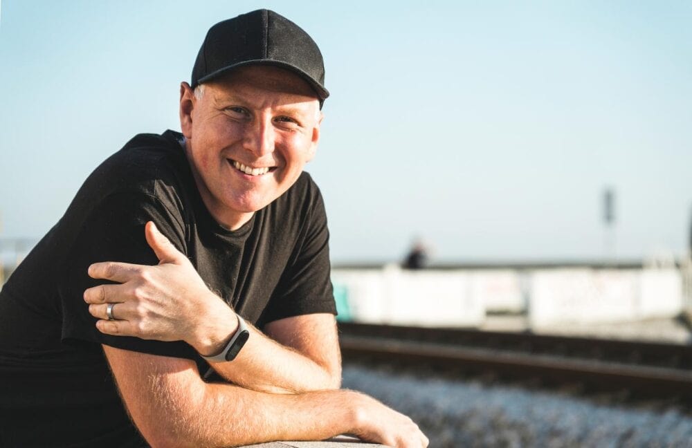 man smiling outside wearing a ball cap